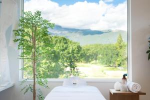Un dormitorio con una gran ventana con un árbol en Vive Boutique Hotel - Echoland, en Hakuba