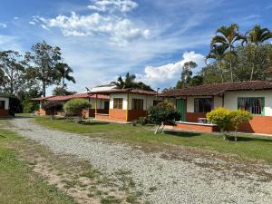 uma casa em uma estrada de cascalho em frente a uma casa em FINCA HOTEL LAS CABAÑAS DEL Parque em Pueblo Tapao