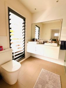 a bathroom with a toilet and a large mirror at Oasis by the Bay - 4 bedroom Beach House in Corlette +36 photos