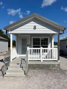 een klein wit huis met een veranda en een trap bij Serene Tiny Home - Biker-Friendly, Close to Skyway in Tellico Plains