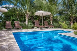 a swimming pool with two chairs and an umbrella at Karana Penthouse - K4 in Providenciales +70 photos