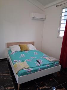 a bedroom with a bed with a blue comforter at Kaz o ti plezi in Sainte-Rose
