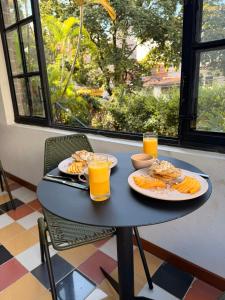 a table with two plates of food and two glasses of orange juice at Casamía in Medellín