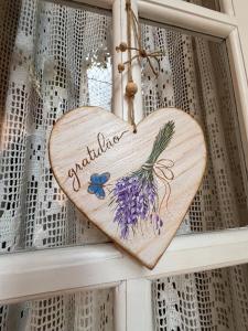 弗洛里亚努元帅镇Cantinho Ítalo-Germânico Hospedagem - Suíte Lavanda - Centro, Marechal Floriano-ES的窗帘上挂着一颗镶有鲜花的木质心形图案