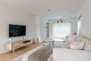 un soggiorno bianco con un divano e una TV di Vakantiewoning Sable Dor a Oostduinkerke