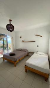 Dos camas en una habitación blanca con ventana. en Casa Kayab, en Puerto Morelos