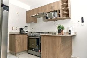 a kitchen with wooden cabinets and a stove top oven at Casa Los Tules No 10 in Ciudad Guzmán