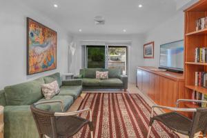 a living room with a couch and a tv at Surfbreak, Culburra Beach in Culburra Beach