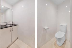 a white bathroom with a toilet and a sink at Surfbreak, Culburra Beach in Culburra Beach +18 photos