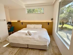 Un dormitorio con una gran cama blanca con ventana. en Vive Boutique Hotel - Echoland, en Hakuba 28 fotos más