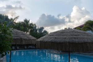 a swimming pool with straw umbrellas and a resort at Le Cottage 61 - Au Bonheur de Sophie in Le Vauclin