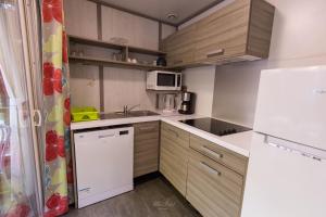 a small kitchen with wooden cabinets and a white refrigerator at Le Cottage 61 - Au Bonheur de Sophie in Le Vauclin