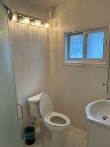 Un baño con inodoro, lavabo y ventana. en Cozy Studio Apartment, en Thunder Bay