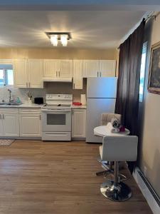 Una cocina con gabinetes blancos y un refrigerador blanco. en Cozy Studio Apartment, en Thunder Bay