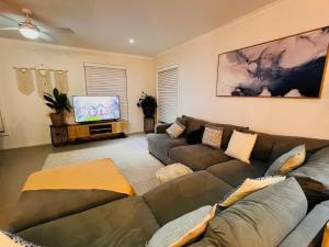 a living room with a couch and a flat screen tv at Oasis by the Bay - 4 bedroom Beach House in Corlette