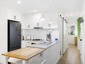 a kitchen with white cabinets and a black refrigerator at Bright 2-Bed Apartment Near Narrabeen Beach in Narrabeen