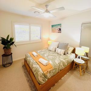 a bedroom with a bed with a ceiling fan at Oasis by the Bay - 4 bedroom Beach House in Corlette