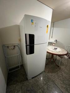 um frigorífico branco numa cozinha com uma mesa em Casa próximo a UFR - QUARTO SALA E COZINHA EQUIPADA em Rondonópolis