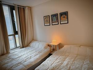 two twin beds in a room with a window at Daejeon Dunsan Starworks in Daejeon