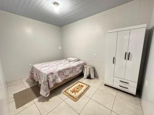 a bedroom with a bed and a cabinet and a rug at Casa com 02 Quartos em Balneário Camboriú in Balneário Camboriú