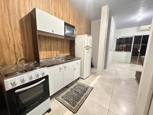 a kitchen with a stove and a sink and a refrigerator at Casa com 02 Quartos em Balneário Camboriú in Balneário Camboriú