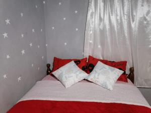 una camera da letto con un letto con cuscini rossi e bianchi di Hermoso departamento de tres dormitorios a Cuenca