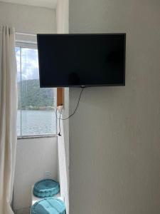 a flat screen tv hanging on a wall with a window at Sobradinho da Lagoa in Niterói