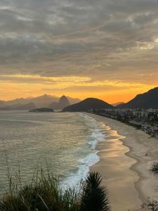 a beach at sunset with mountains in the background at Sobradinho da Lagoa in Niterói