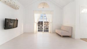 a white living room with a couch and a tv at Taean Dokchae Trudy Pension in Taean