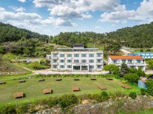 a large white building with benches in a field at Namhae Camp Village in Namhae