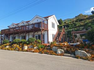 a house with a balcony on the side of the road at Yeosu Geumodo Badaae Pension in Yeosu +1 photo