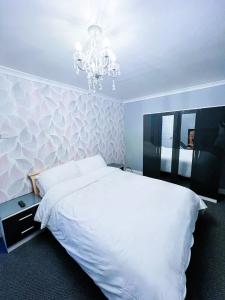 una camera da letto con un letto bianco e un lampadario di Mona a Hull