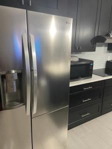 a stainless steel refrigerator in a kitchen with black cabinets at Orlando 4 bedroom built in 2021 in Orlando