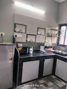 a kitchen with a black counter top and a refrigerator at Ferns home stay in Betalbatim