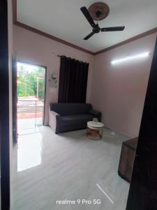 a living room with a couch and a ceiling fan at Ferns home stay in Betalbatim