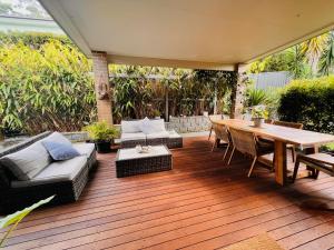 a wooden deck with a table and chairs on it at Oasis by the Bay - 4 bedroom Beach House in Corlette