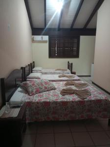 a room with three beds with towels on them at Vô Doríbio in Torres