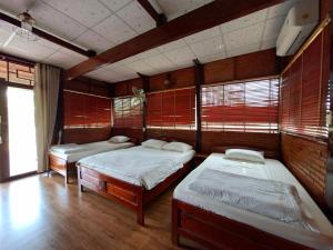 a room with three beds in it with windows at Cát Tiên Riverside in Tân Phú