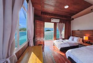 Starz Water Village仙本那星星美亚水屋 في سيمبورنا: غرفة نوم بسريرين وإطلالة على المحيط