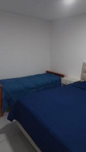 two beds with blue sheets in a room at Macarena in La Falda