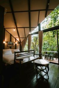 清迈Voraman B-One的一间卧室配有一张床、一张长凳和一个窗户。