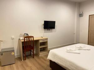 Una habitación con una cama y un escritorio con televisión. en Crystal Resort Korat, en Nakhon Ratchasima