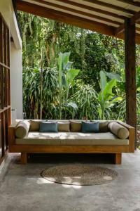 a couch sitting on a patio in a garden at Mountain Villa & Nature Retreat - Fleur de Vie in Bedugul