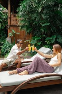 a man and woman sitting on a boat with drinks at Aryaswara Villa Ubud in Ubud