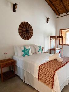 una camera da letto con un grande letto bianco con cuscini blu di Pousada Aconchego a Caraíva