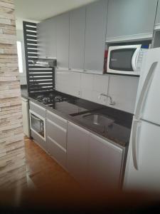 une cuisine avec un évier et un micro-ondes dans l'établissement Apartamento Premium Torres-Rs, à Torres