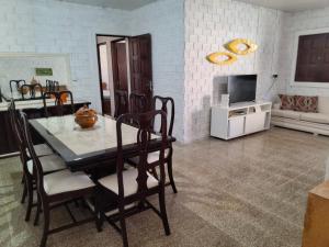 ein Esszimmer mit Tisch und Stühlen und einem Fernseher in der Unterkunft Casa de Veraneio com 4 quartos in Barra de São Miguel
