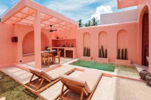 ein rosa Haus mit Swimmingpool, Tisch und Stühlen in der Unterkunft Villa Solea in Gili Trawangan