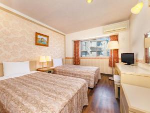 伊東市にあるAMBIENT 伊豆高原 コンドミニアムのベッド2台とテレビがあるホテルの部屋
