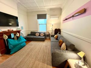 un soggiorno con un divano e una TV di Kerrigan's on Seaview- one minute walk to beach - not beachfront views a Henley Beach South